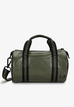 Bolsa de lona cilíndrica verde con asas dobles negras, correa de hombro ajustable a rayas y pequeño logo de corona de laurel negra en un extremo.
