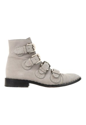 Bottine en daim gris clair avec quatre boucles et clous argentés, semelle noire et petit talon.