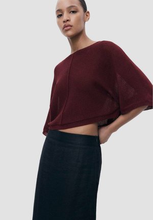 Bordeaux cropped trui met een boxy ontwerp, textuurgebreide stof en brede mouwen, gecombineerd met een zwarte hooggepreekte rok.