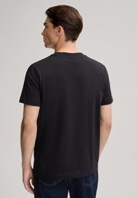 Zwart t-shirt met korte mouwen en een klassieke ronde hals, gemaakt van zachte katoen. Bevat een klein rood logo aan de onderzijde.