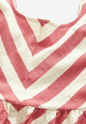 Červenobiely pruhovaný textil s textúrovaným povrchom, ktorý obsahuje vzor v tvare šípky a na spodnom okraji má zhrnutú volánovú ozdobu.