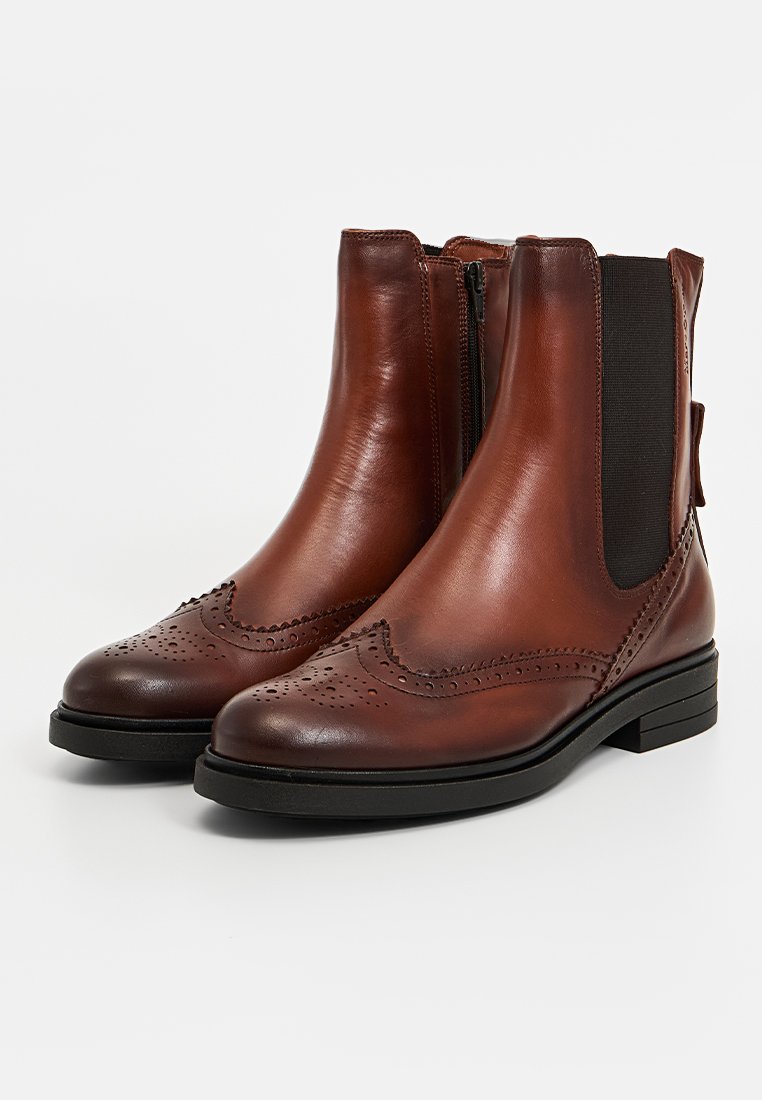 Braune Leder-Stiefeletten mit glatter Oberfläche, elastischen Seitenpaneelen und dekorativen Broguedetails, ausgestattet mit einem niedrigen schwarzen Absatz.