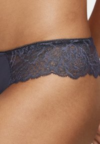 Granatowa bielizna z koronkową lamówką zdobioną kwiatowymi wzorami, z falistymi krawędziami i gładką fakturą materiału zapewniającą komfort.