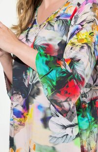 Blomsterprydd topp med klara färger, V-ringning och trekvartsärmar, tillverkad av lättviktig tyg med en mjuk textur.