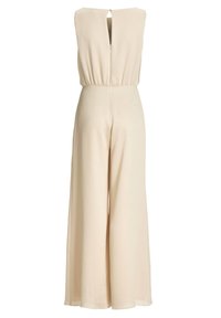 Combinaison beige sans manches à jambes larges, taille haute et fermeture au dos par bouton avec ouverture goutte d'eau, confectionnée en tissu léger texturé.