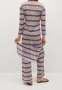 Ensemble tissé en deux pièces comprenant un long tunique et un pantalon avec des motifs en zigzag violet, bleu et beige. Léger, avec des manches longues et une écharpe fluide.