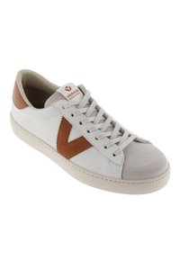 Baskets blanches avec des accents en daim marron, bout gris clair et lacets. Présente un logo marron bien en vue sur le côté et un design de semelle cousue.