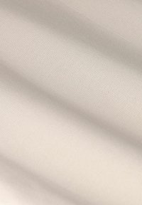 Tissu lisse de couleur crème avec un tissage texturé subtil, montrant de douces ondulations et plis, indiquant un matériau léger.