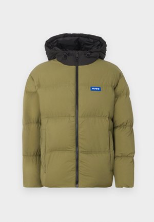 Olivengrøn pufferjakke med sort hætte, frontlynlås og et blåt logo-patch. Har syede sektioner og en glat tekstur.