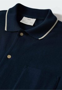 Polo shirt blu navy in tessuto strutturato, con patta a tre bottoni, rifiniture a contrasto nel colletto e una tasca singola sul petto.