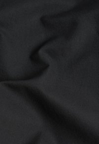 Tissu noir avec une texture lisse, affichant de légers plis et un fini mat uniforme, adapté à diverses applications.