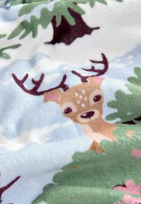 Coperta in fleece con uno sfondo azzurro chiaro, alberi verdi e un cervo cartone con macchie marroni e corna prominenti, tra fiori rosa.