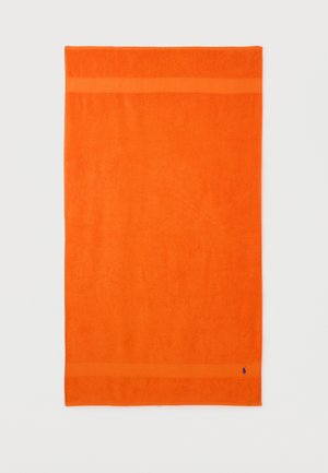 Toalla rectangular de color naranja brillante con dos franjas horizontales cerca de los bordes y un pequeño logo azul marino en la esquina inferior derecha.