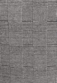 Textilmuster mit abwechselnden Quadraten aus feinen Linien und Hahnentritt in Schwarz und Weiß, das ein strukturiertes, geometrisches Design erzeugt.
