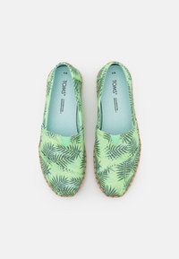 Sapatos slip-on verde menta com padrão de folha de palmeira, parte superior em lona, detalhes elásticos laterais e sola em fibra natural.