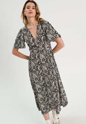 Schwarz-weißes Blumenkleid mit kurzen Ärmeln, V-Ausschnitt und tailliertem Bund. Hergestellt aus leichtem Stoff, mit einem fließenden Rock.