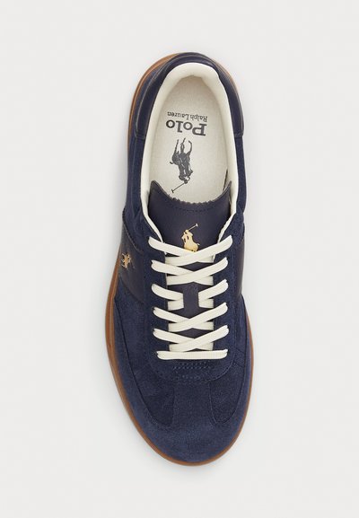 Navy blue suede sneaker with white laces, brown sole, and Polo Ralph Lauren logo on tongue, side, and insole.