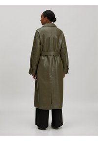 Olijfgroene leren trenchcoat met een ceintuur in de taille, lange mouwen en een rugventilatie. Voorzien van een kraag en een licht glanzende textuur.