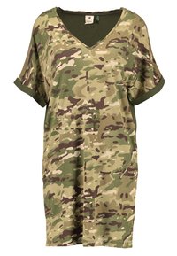 Robe T-shirt surdimensionnée à motifs camouflage dans des nuances de vert et de marron, avec un col en V et des manches courtes retroussées. Fabriquée en tissu doux.