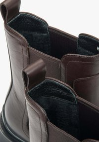 Hnědé kožené kotníkové boty s hladkým povrchem, měkkou černou podšívkou a textilními poutky pro snadné obutí.