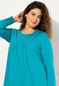 Turquoise langemouwen top met een ronde halslijn, geplooid detail met fijne stiksels en een relaxte pasvorm. Glad, zacht stofoppervlak.