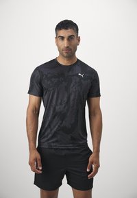 Schwarzes sportliches T-Shirt mit strukturiertem Muster, kurzen Ärmeln und rundem Ausschnitt; mit einem weißen Puma-Logo auf der Brust.
