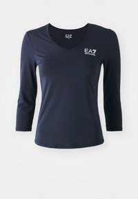 Tengerészkék, hosszú ujjú felső, V-nyakkivágással, sima anyagból készült. Az EA7 logó a mellkason található, és a fazonja testhezálló, egyszerű, letisztult vonalakkal.