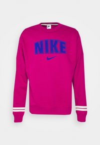 Sudadera de color rosa brillante con texto y logo "NIKE" en azul. Presenta franjas blancas en las mangas y puños y dobladillo acanalados. Material de algodón.