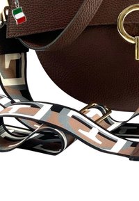 Bruine leren tas met een ronde vorm, gouden hardware en een gestreepte stoffen schouderband in beige, zwart en witte tinten.