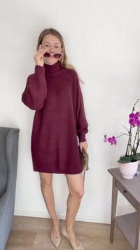 Vestido de malha oversized burgundy com textura canelada, mangas até ao cotovelo, combinado com saltos nude e óculos de sol. Orquídeas cor-de-rosa em vaso nas proximidades.