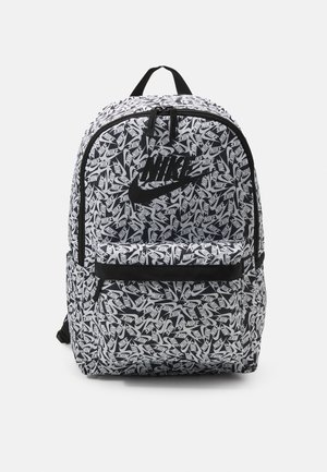 Sac à dos avec motif du logo Nike en noir et blanc, grande poche avant, poignée supérieure et bretelles réglables sur fond uni.