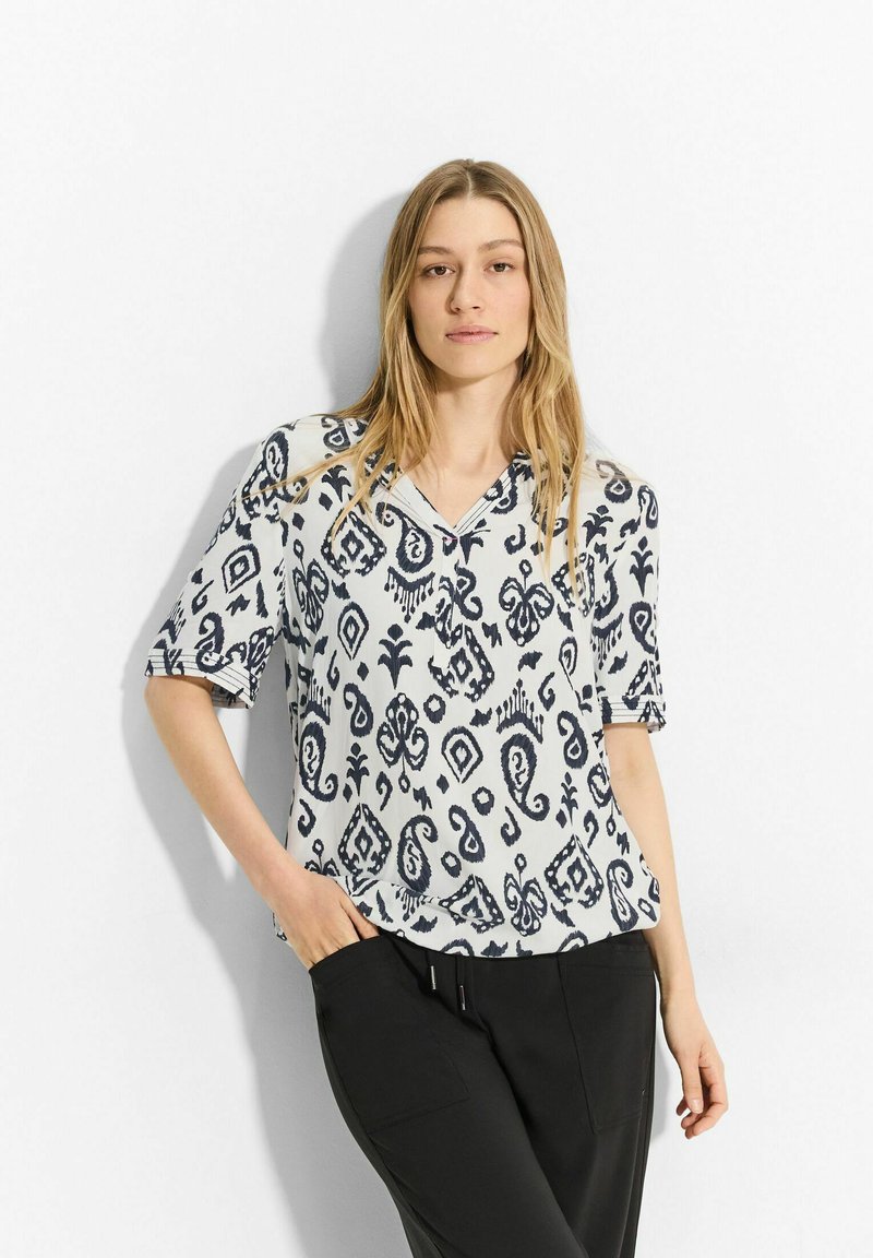 Blusa de manga corta con un patrón abstracto en azul marino y blanco. Presenta un escote en V y un corte relajado. Fabricada con un tejido ligero.