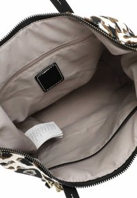 Reißverschluss-Handtasche mit einem schwarz-weißen Leopardenmuster außen. Das Innere verfügt über eine beigefarbene Stoffauskleidung, eine Reißverschlusstasche und ein Pflegeetikett.