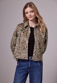 Veste en tissu doux à imprimé léopard, avec un devant boutonné, un col pointu et deux poches poitrine. Associée à un jean dark.