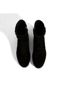 Zwarte suede enkellaarsjes met een soepele textuur, voorzien van een zijrits en een zilveren gespaccent. Rond neus en een laag hakontwerp.