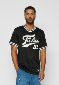 Melna sietu džersija ar baltu "Fubu" logo un "05" uz priekšpuses. Īsas piedurknes ar baltām svītrām un V veida kakla izgriezums.