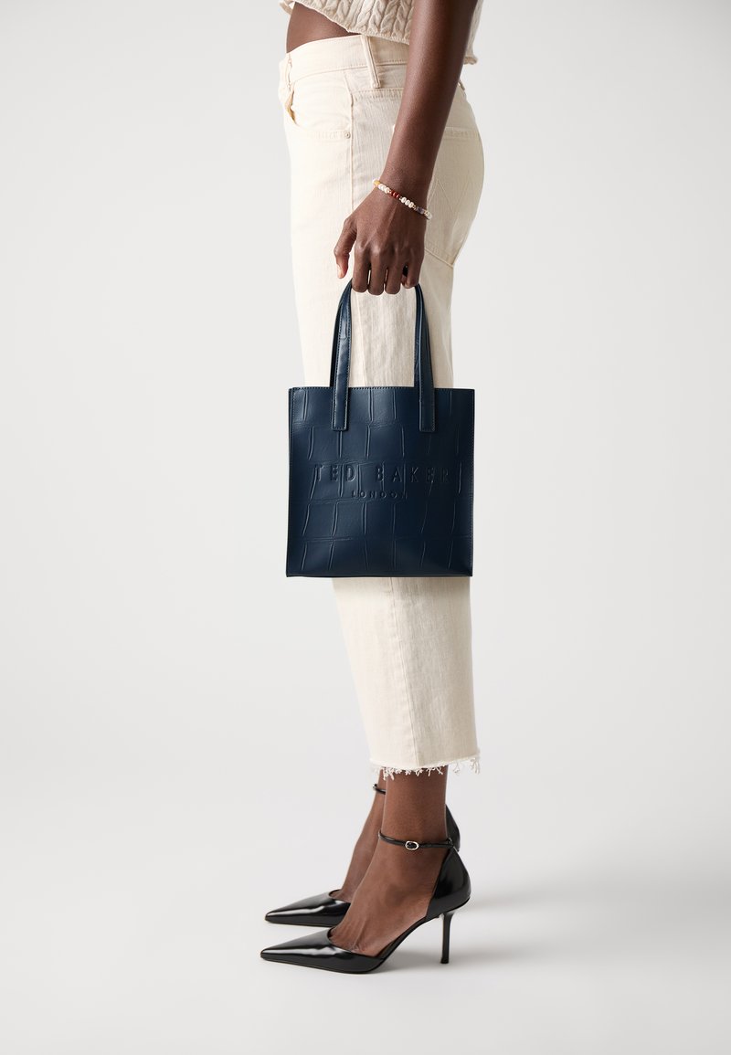 Borsa a spalla in ecopelle blu navy con marchio impresso e motivo coccodrillo. Presenta due manici corti e un design strutturato.