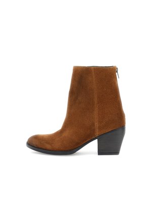 Stivale alla caviglia in suede marrone con punta arrotondata, tacco di altezza media e chiusura con zip laterale. Texture liscia e cuciture minimali.