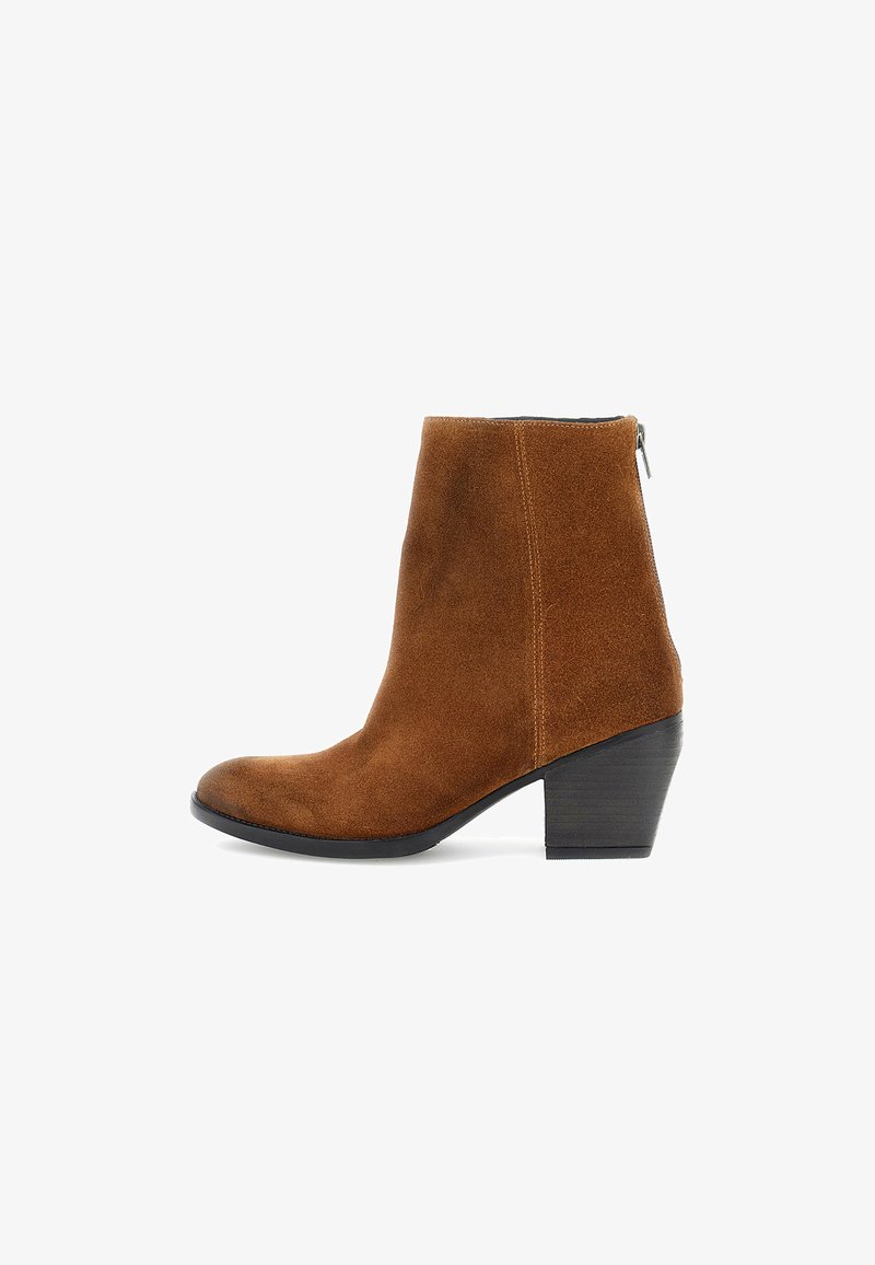 Botín de ante marrón hasta el tobillo con punta redondeada, tacón de altura media y cierre de cremallera lateral. Textura suave y acentos de costura mínima.