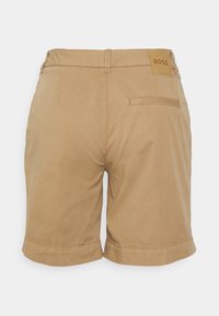 Beige herrcasual shorts med en bakficka och en läderpatch på midjebandet som står "BOSS" på en vit bakgrund.
