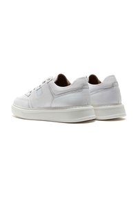 Sneakers bianchi in pelle con profilo basso, punta rotonda, chiusura con lacci e lati testurizzati; presentano una suola in gomma bianca e accenti minimi.