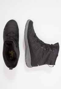 Schwarze Outdoor-Stiefel mit strukturiertem Obermaterial aus Stoff, Gummisohle und gepolstertem Innenfutter. Verfügt über ein Schnürdesign und eine Zuglasche an der Ferse.