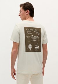 Helles beiges Baumwoll-T-Shirt mit einem braunen Grafikdruck auf der Rückseite, der sommerliche Illustrationen und Text zeigt. Runder Halsauschnitt, kurze Ärmel.
