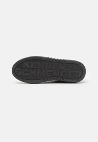 Zwarte rubberen schoenzool met gestructureerde grippatronen en het geperste "KENNEL SCHMENGER" logo. Rond gevormd met duidelijke randen.