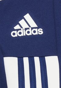 Marineblaue Sportoberteil mit weißem Adidas-Logo, aus strukturiertem Material gefertigt und mit drei weißen vertikalen Streifen im unteren Bereich.