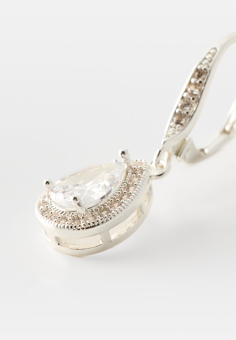 Orecchino in argento con una grande pietra preziosa trasparente a forma di pera circondata da piccole pietre trasparenti su uno sfondo bianco.
