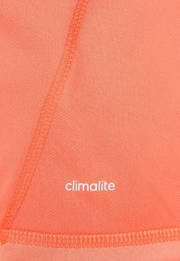Tejido Climalite de color naranja con un patrón texturizado. Costuras suaves y un logo blanco colocado cerca de la parte inferior. Material ligero y transpirable.