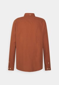 Chemise à manches longues en tissu couleur rouille, dotée d'un col boutonné, de poignets à un bouton et d'une texture lisse, vue de dos.