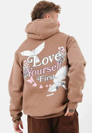 Brauner Hoodie mit weißem und pinkem Text "Love Yourself First", verziert mit floralen Grafiken und Tauben. Weicher Stoff, lässiger Schnitt und Kapuzen-Design.