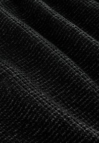 Juodas tekstūruotas audinys su audimo raštu, rodantis švelnų, šiek tiek pūkuotą paviršių ir subtilų blizgesį, sudėtas švelniuose raukšlėse.